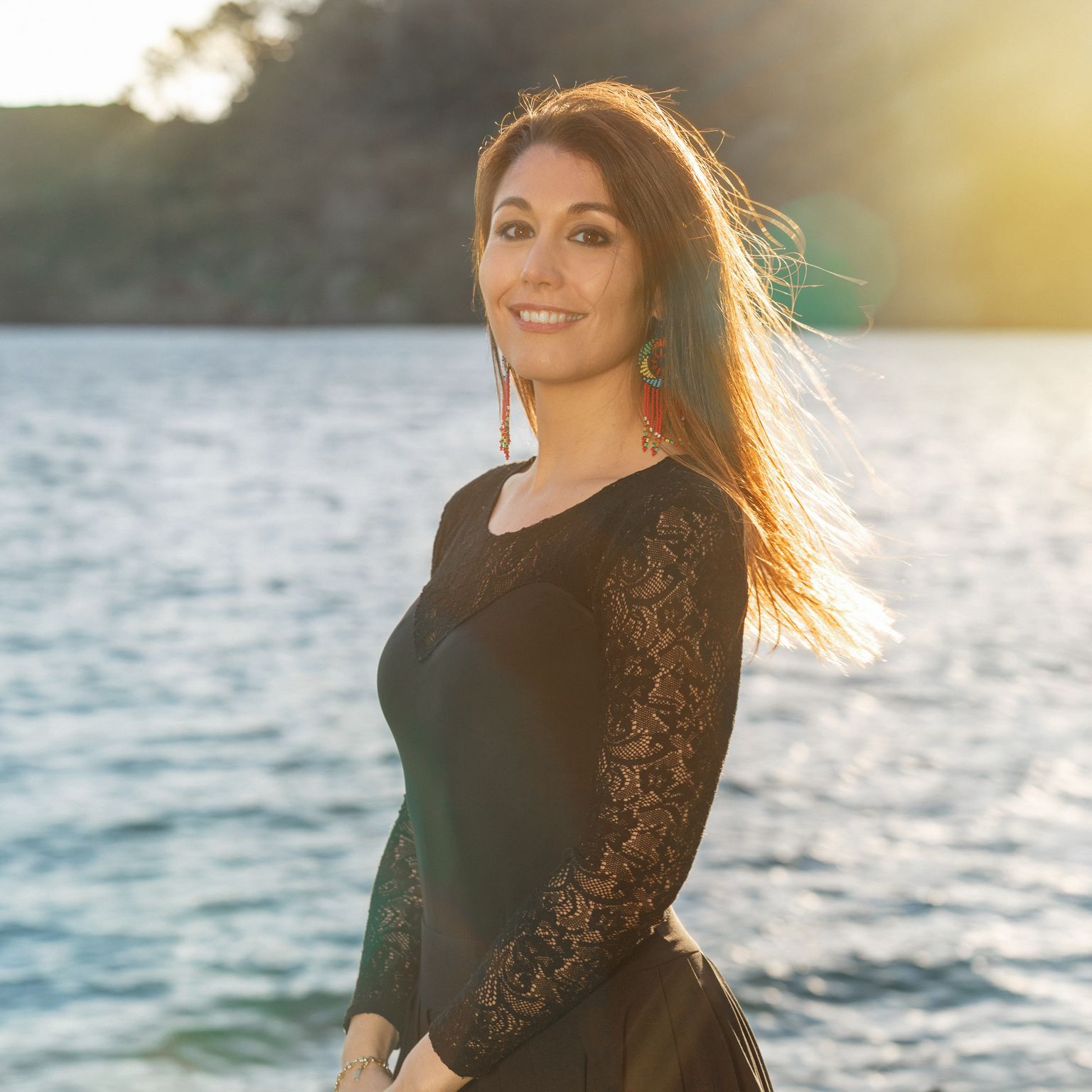 Alma standing by the sea in the evening light, smiling