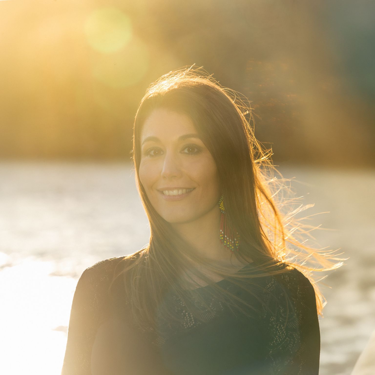 Alma smiling in warm golden evening light by the water